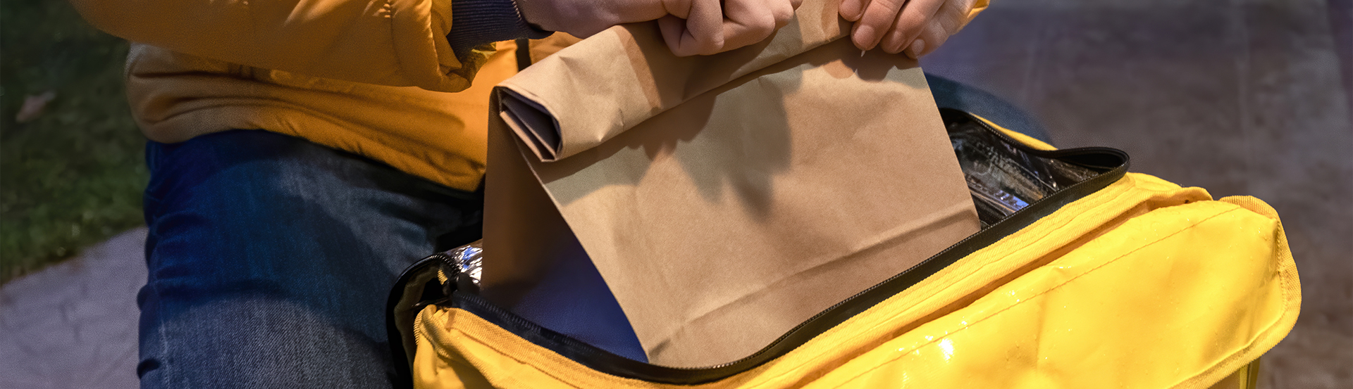 Ghostacos-Lieferfahrer, der eine Papiertüte mit French Tacos in seine Liefertasche legt, bereit zur Auslieferung an Kunden über Partner wie Smood, UberEats, Just Eat, Velogourmet und FOOD HERO